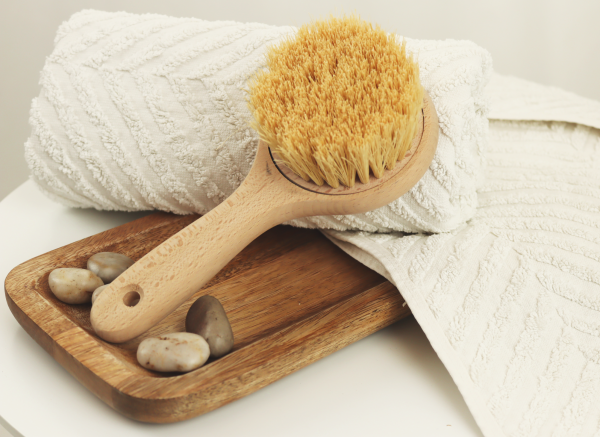 Handgemachte Saune-/Körperbürste auf weißem Handtuch und Holzbrett